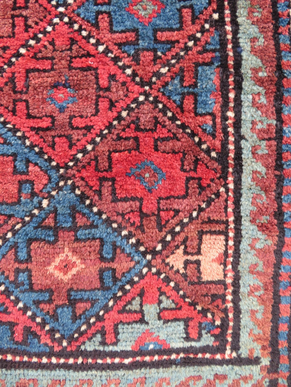 An antique hand-knotted Quchan Kurdish wool rug displaying a central diamond pattern inside a dark red and navy lattice grid with geometric borders. View XV