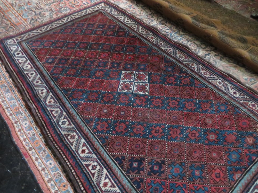 An antique hand-knotted Quchan Kurdish wool rug displaying a central diamond pattern inside a dark red and navy lattice grid with geometric borders. View XVII