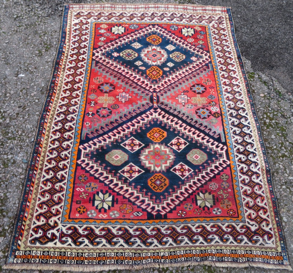 A handwoven Luri tribal rug featuring double geometric diamond medallions in navy blue and red with multi-layered patterned borders. View II