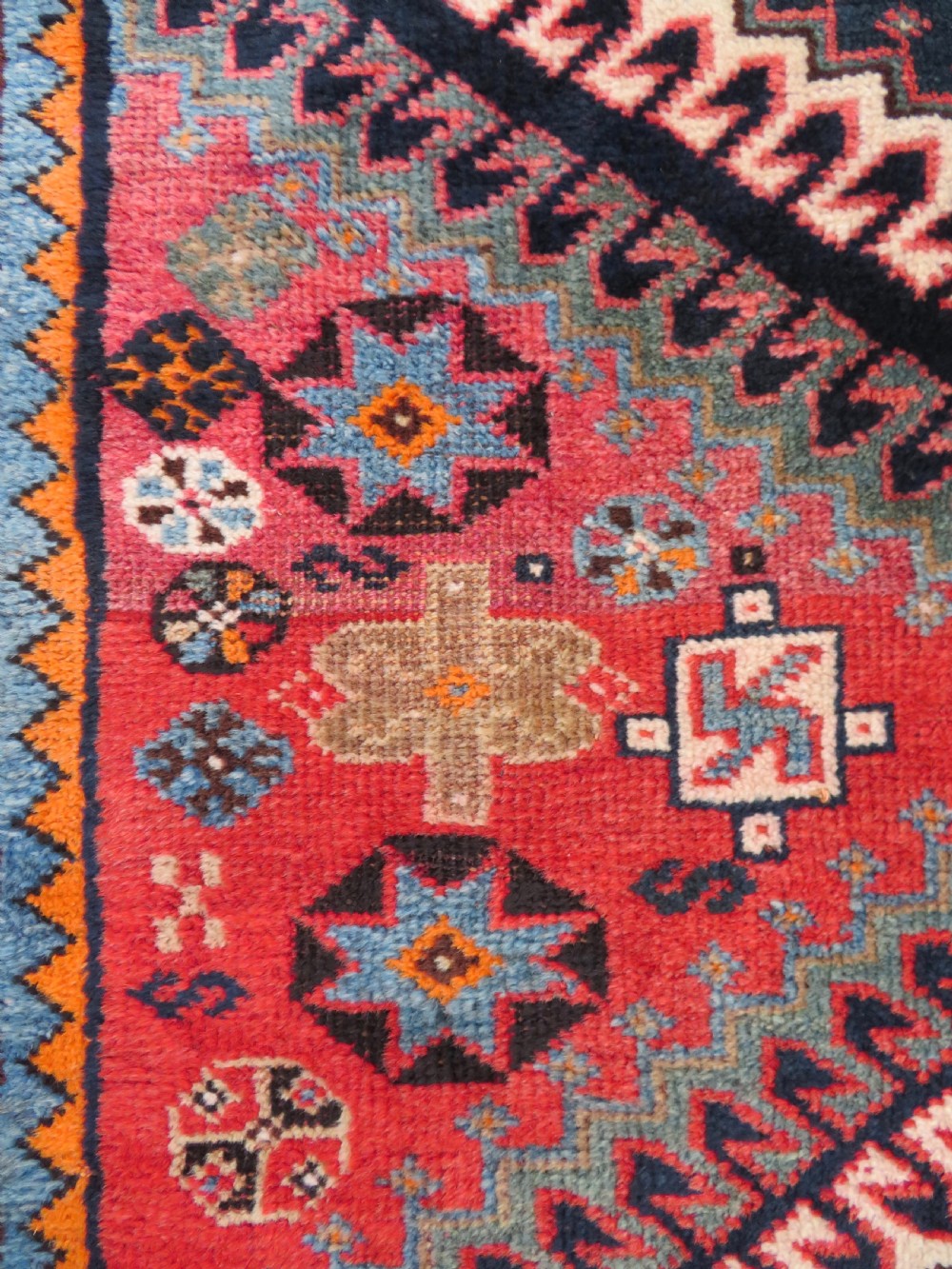 A handwoven Luri tribal rug featuring double geometric diamond medallions in navy blue and red with multi-layered patterned borders. View IV