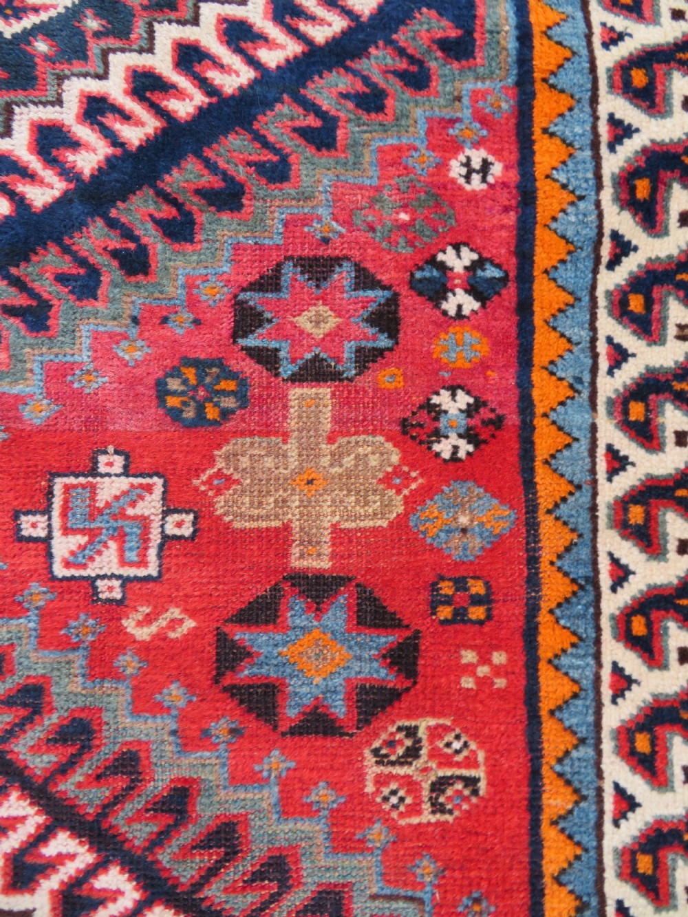 A handwoven Luri tribal rug featuring double geometric diamond medallions in navy blue and red with multi-layered patterned borders. View VI
