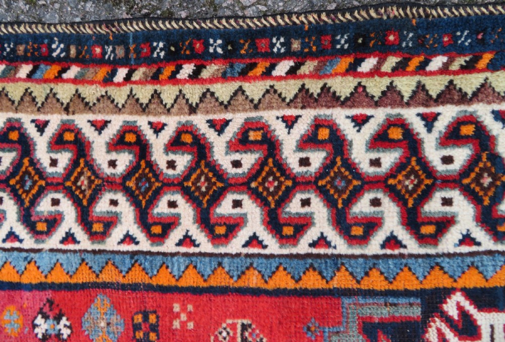 A handwoven Luri tribal rug featuring double geometric diamond medallions in navy blue and red with multi-layered patterned borders. View VII