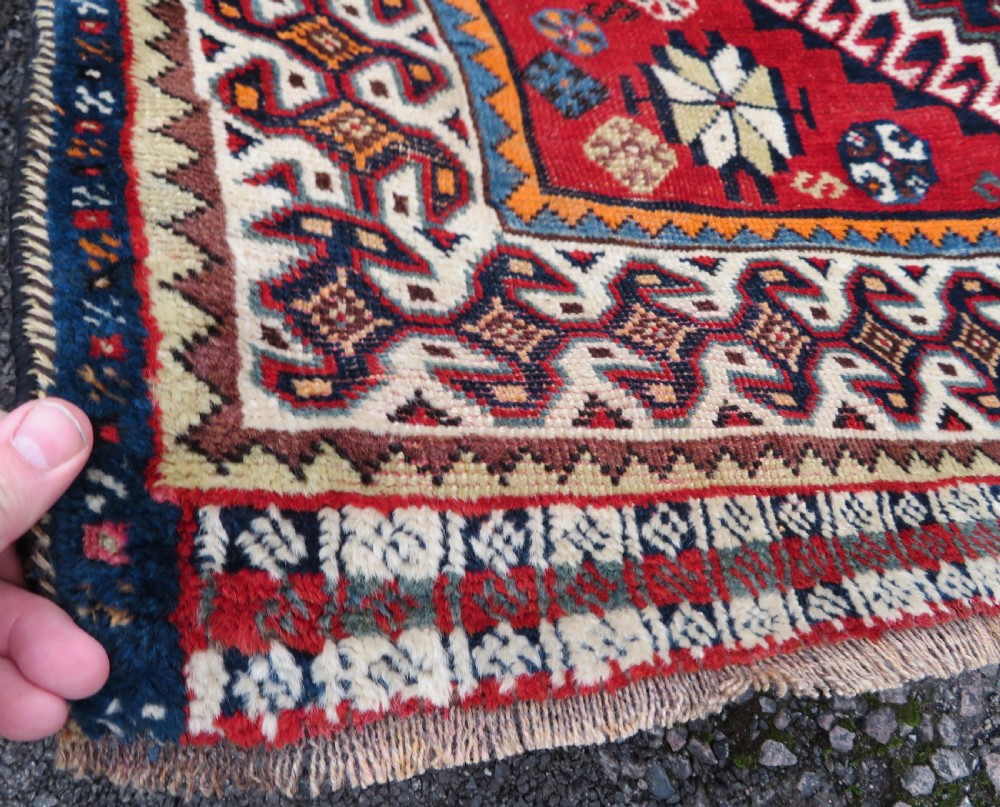 A handwoven Luri tribal rug featuring double geometric diamond medallions in navy blue and red with multi-layered patterned borders. View VIII
