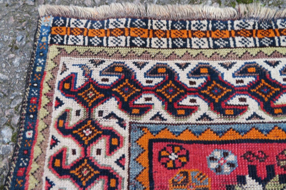 A handwoven Luri tribal rug featuring double geometric diamond medallions in navy blue and red with multi-layered patterned borders. View X