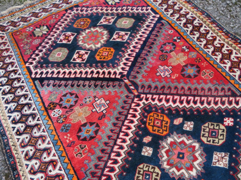 A handwoven Luri tribal rug featuring double geometric diamond medallions in navy blue and red with multi-layered patterned borders. View XV