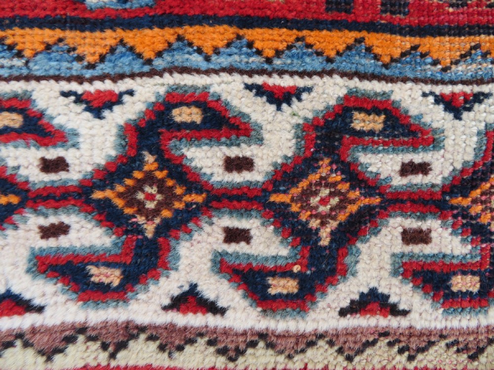 A handwoven Luri tribal rug featuring double geometric diamond medallions in navy blue and red with multi-layered patterned borders. View XVII