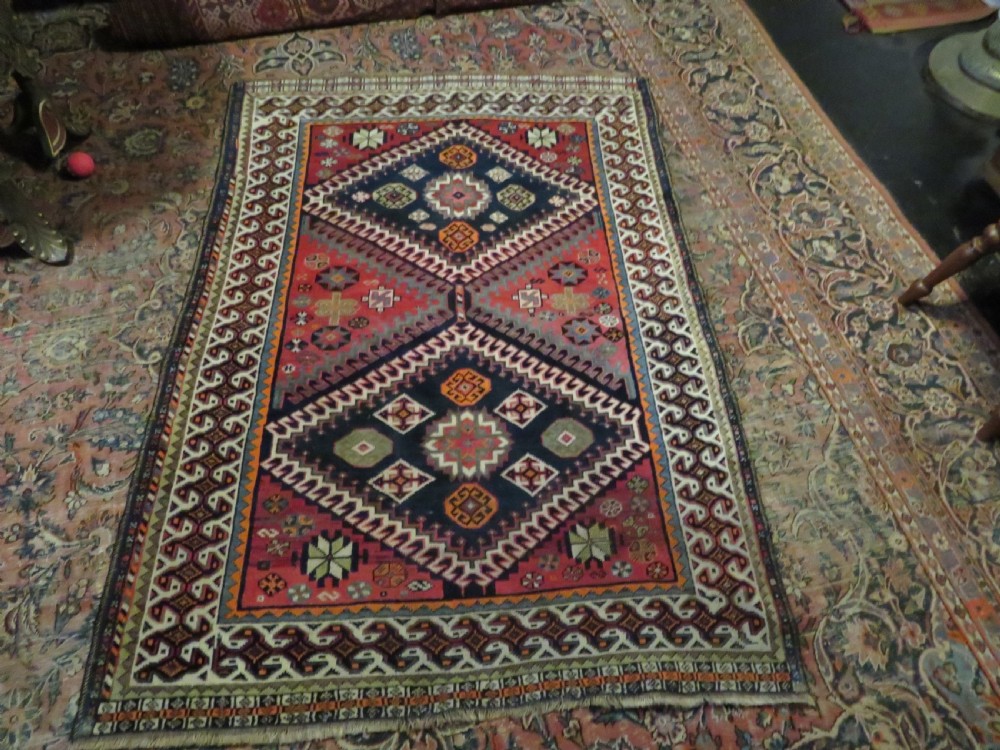 A handwoven Luri tribal rug featuring double geometric diamond medallions in navy blue and red with multi-layered patterned borders. View XXIV