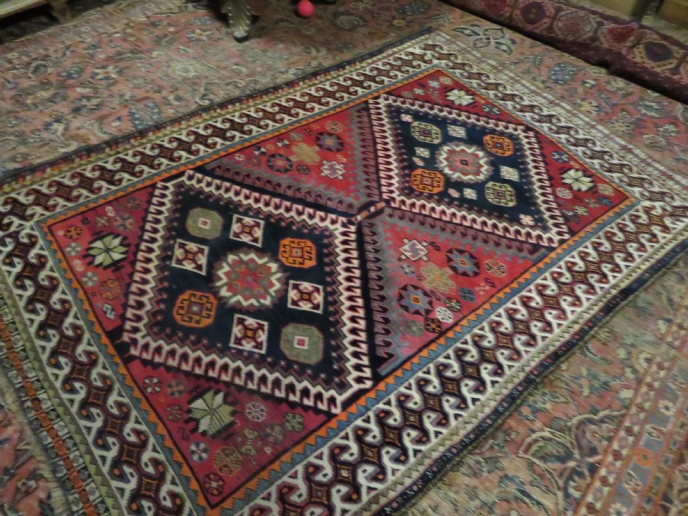 A handwoven Luri tribal rug featuring double geometric diamond medallions in navy blue and red with multi-layered patterned borders. View XXV