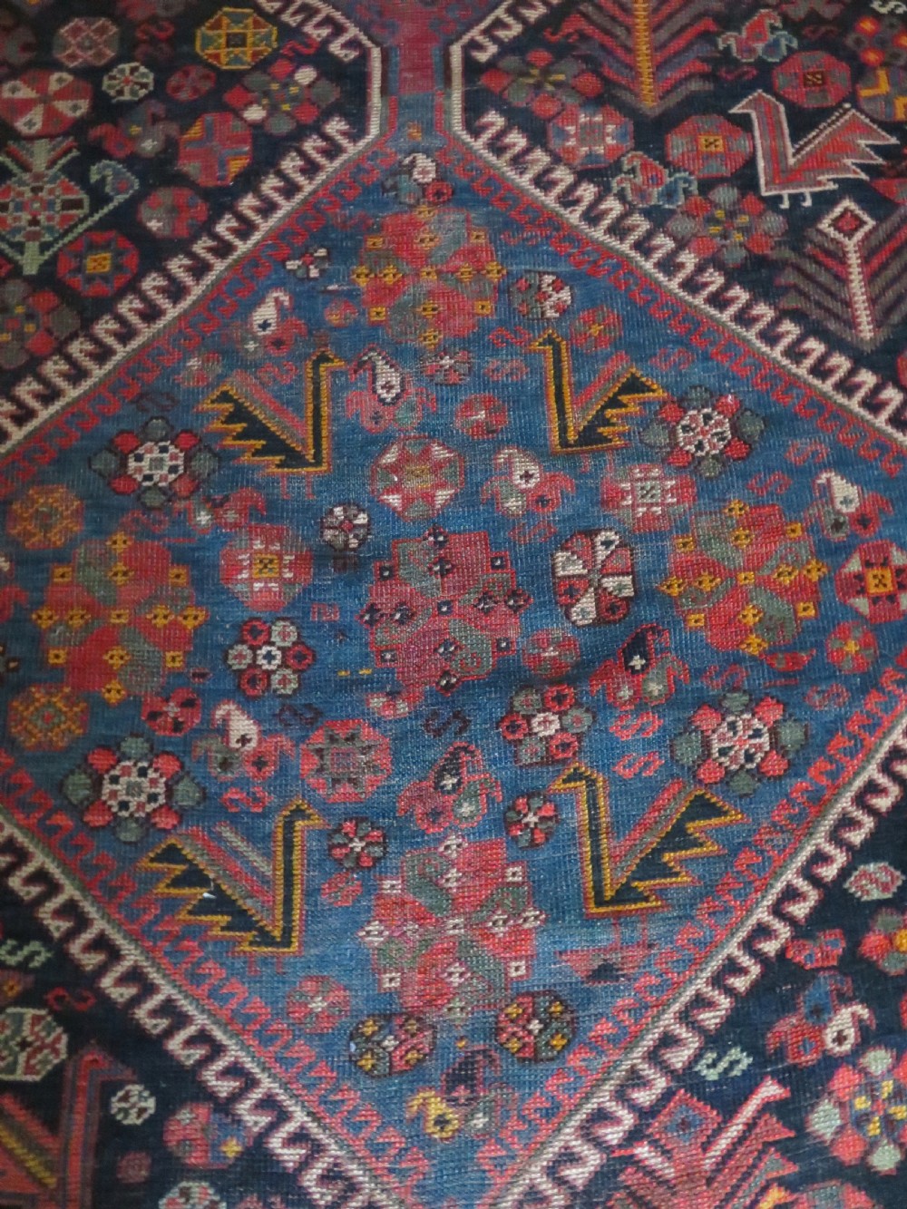 An antique hand-knotted Qashqai wool rug featuring three diamond central medallions with tribal peacock motifs in red, blue, and magenta tones. View VIII