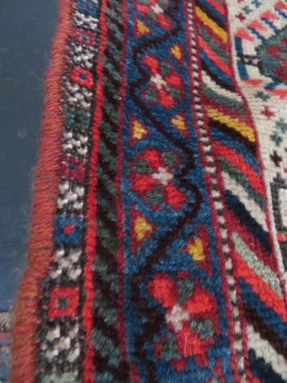 An antique hand-knotted Qashqai wool rug featuring three diamond central medallions with tribal peacock motifs in red, blue, and magenta tones. View XV