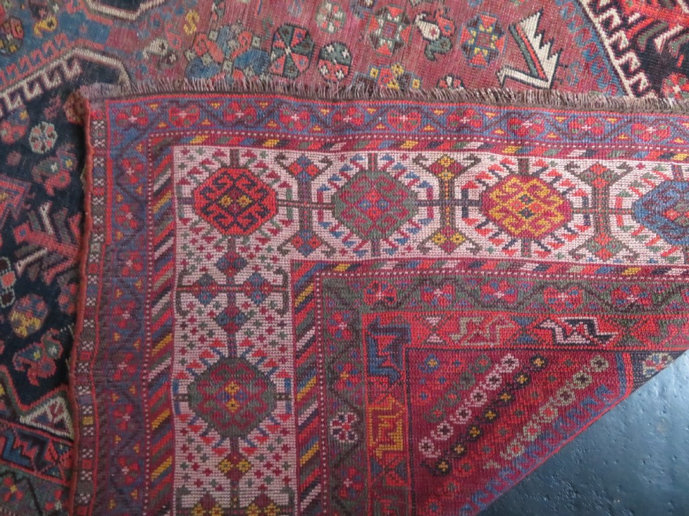An antique hand-knotted Qashqai wool rug featuring three diamond central medallions with tribal peacock motifs in red, blue, and magenta tones. View XVI