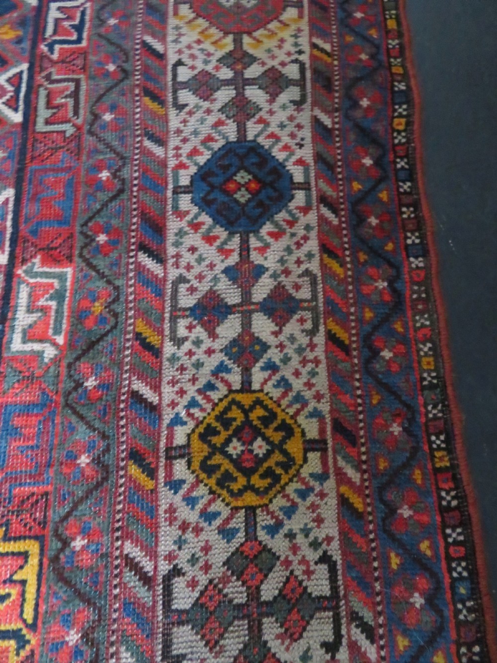 An antique hand-knotted Qashqai wool rug featuring three diamond central medallions with tribal peacock motifs in red, blue, and magenta tones. View XX