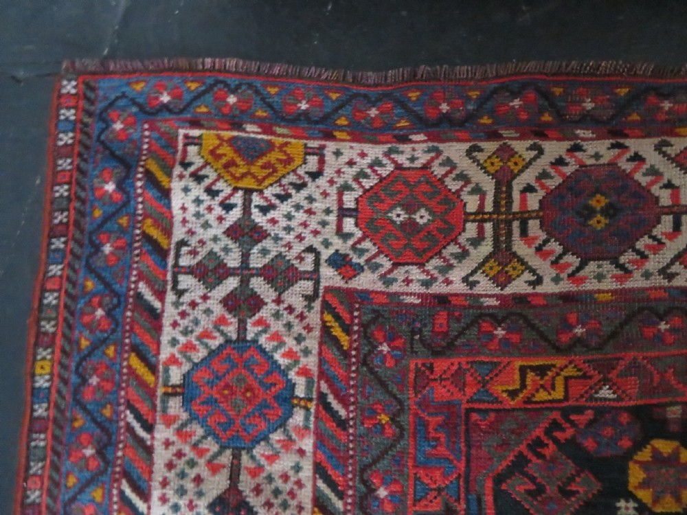 An antique hand-knotted Qashqai wool rug featuring three diamond central medallions with tribal peacock motifs in red, blue, and magenta tones. View XXII