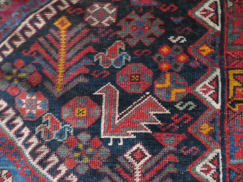 An antique hand-knotted Qashqai wool rug featuring three diamond central medallions with tribal peacock motifs in red, blue, and magenta tones. View XXVI