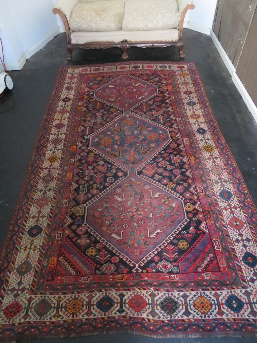 An antique hand-knotted Qashqai wool rug featuring three diamond central medallions with tribal peacock motifs in red, blue, and magenta tones. View XXXI