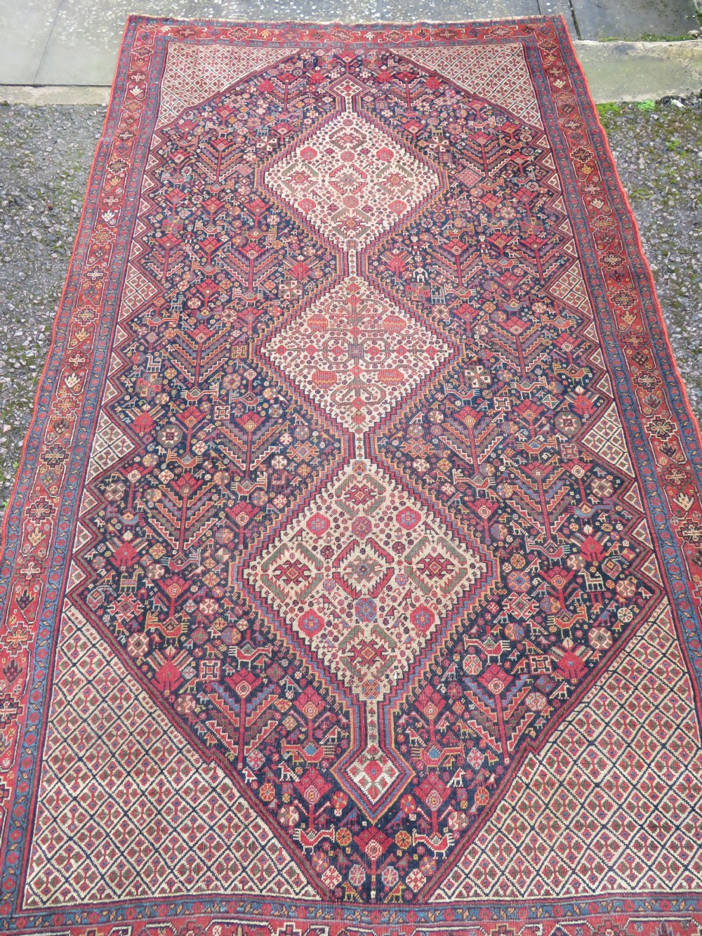 A nineteenth-century hand-knotted Khamseh tribal carpet featuring three diamond-shaped central medallions on an indigo blue field surrounded by geometric borders. View II