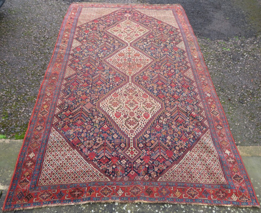 A nineteenth-century hand-knotted Khamseh tribal carpet featuring three diamond-shaped central medallions on an indigo blue field surrounded by geometric borders. View III