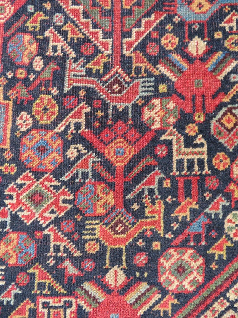 A nineteenth-century hand-knotted Khamseh tribal carpet featuring three diamond-shaped central medallions on an indigo blue field surrounded by geometric borders. View V
