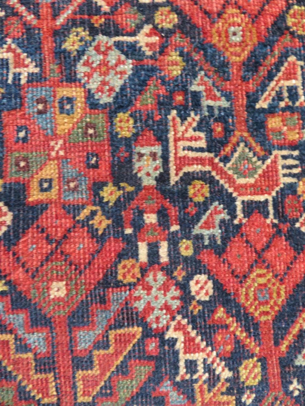 A nineteenth-century hand-knotted Khamseh tribal carpet featuring three diamond-shaped central medallions on an indigo blue field surrounded by geometric borders. View VI