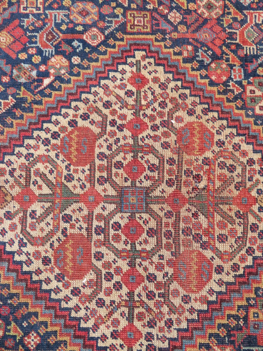 A nineteenth-century hand-knotted Khamseh tribal carpet featuring three diamond-shaped central medallions on an indigo blue field surrounded by geometric borders. View VIII