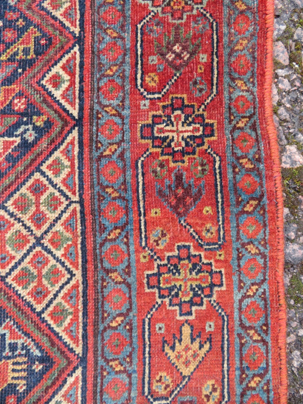 A nineteenth-century hand-knotted Khamseh tribal carpet featuring three diamond-shaped central medallions on an indigo blue field surrounded by geometric borders. View IX