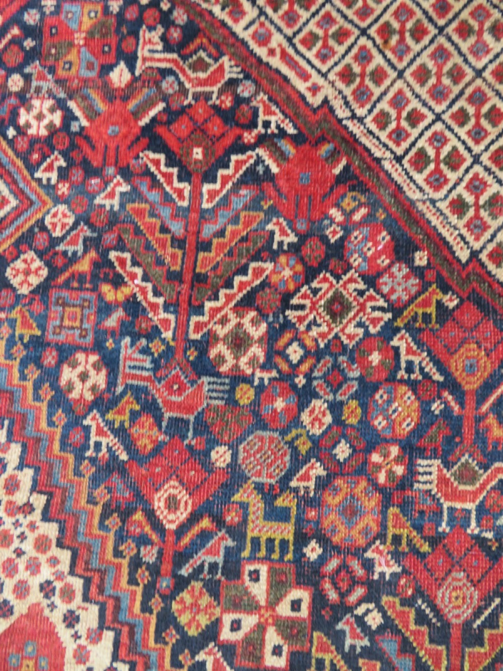 A nineteenth-century hand-knotted Khamseh tribal carpet featuring three diamond-shaped central medallions on an indigo blue field surrounded by geometric borders. View X
