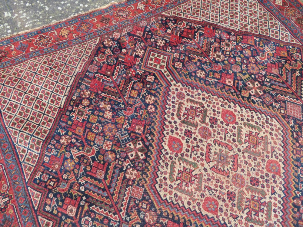 A nineteenth-century hand-knotted Khamseh tribal carpet featuring three diamond-shaped central medallions on an indigo blue field surrounded by geometric borders. View XII