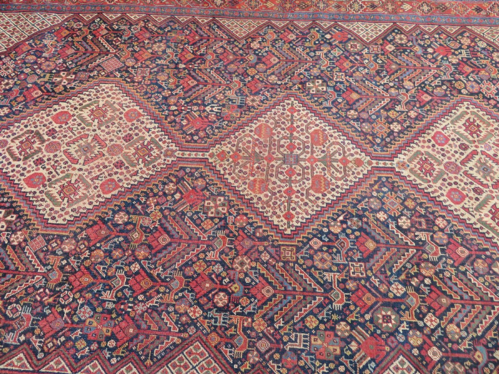 A nineteenth-century hand-knotted Khamseh tribal carpet featuring three diamond-shaped central medallions on an indigo blue field surrounded by geometric borders. View XIII