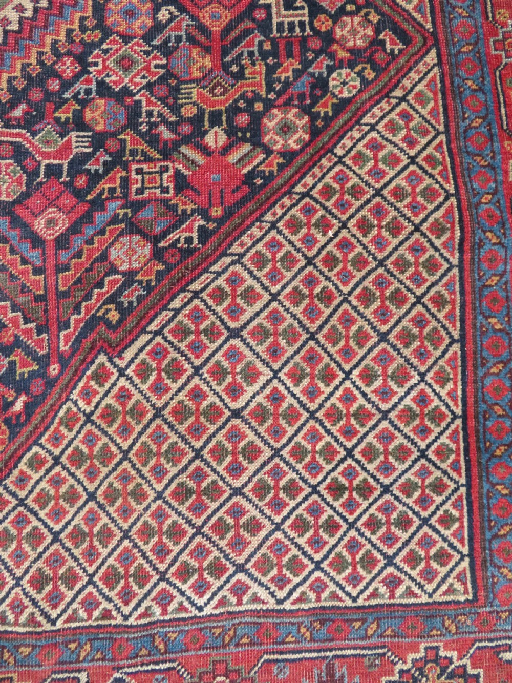A nineteenth-century hand-knotted Khamseh tribal carpet featuring three diamond-shaped central medallions on an indigo blue field surrounded by geometric borders. View XV
