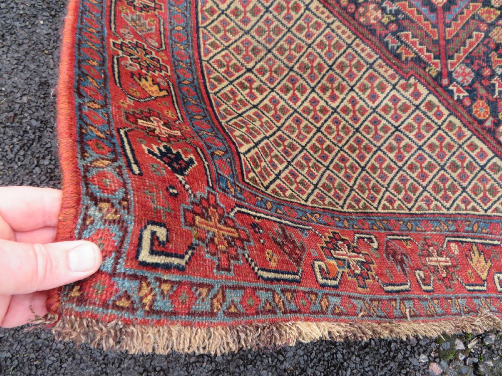 A nineteenth-century hand-knotted Khamseh tribal carpet featuring three diamond-shaped central medallions on an indigo blue field surrounded by geometric borders. View XVI