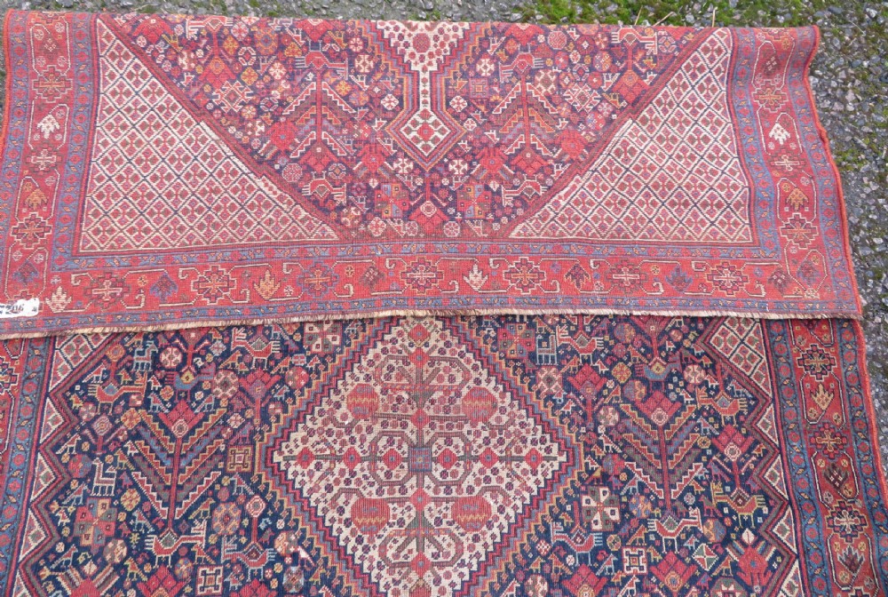 A nineteenth-century hand-knotted Khamseh tribal carpet featuring three diamond-shaped central medallions on an indigo blue field surrounded by geometric borders. View XIX