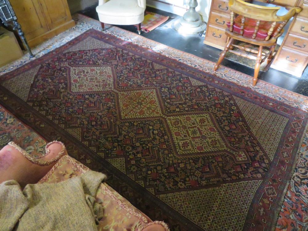 A nineteenth-century hand-knotted Khamseh tribal carpet featuring three diamond-shaped central medallions on an indigo blue field surrounded by geometric borders. View XXX