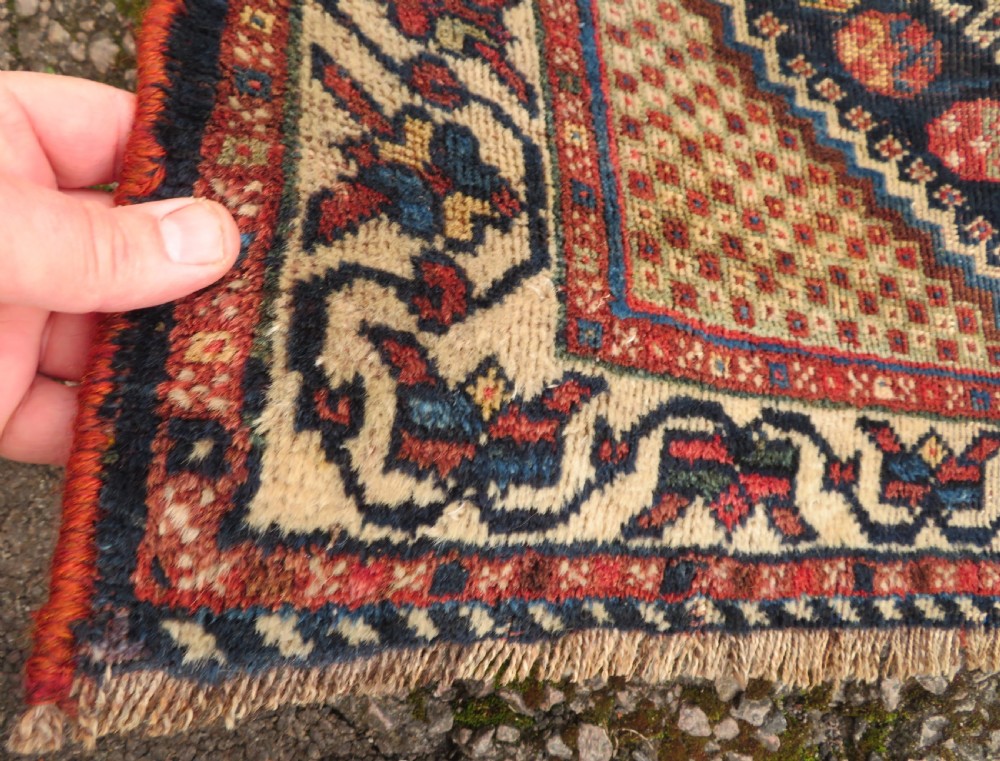 An antique hand-knotted Persian tribal rug featuring three central diamond-shaped medallions, geometric peacock motifs, and multi-layered borders in navy blue, red, and ivory wool. View V