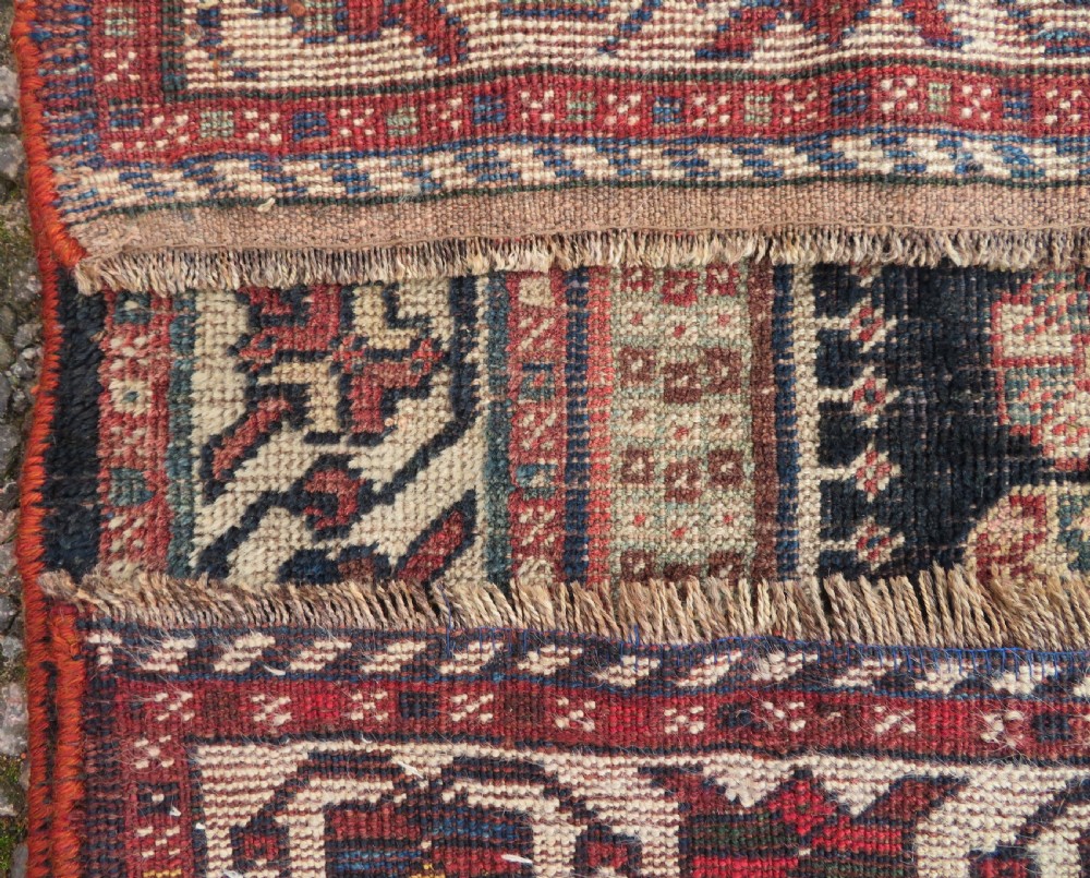 An antique hand-knotted Persian tribal rug featuring three central diamond-shaped medallions, geometric peacock motifs, and multi-layered borders in navy blue, red, and ivory wool. View VIII