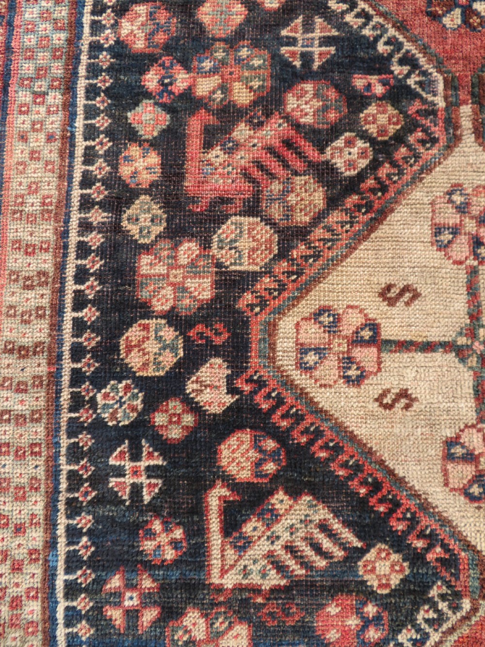 An antique hand-knotted Persian tribal rug featuring three central diamond-shaped medallions, geometric peacock motifs, and multi-layered borders in navy blue, red, and ivory wool. View X