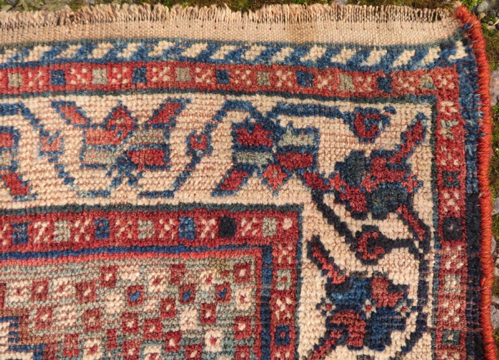 An antique hand-knotted Persian tribal rug featuring three central diamond-shaped medallions, geometric peacock motifs, and multi-layered borders in navy blue, red, and ivory wool. View XI