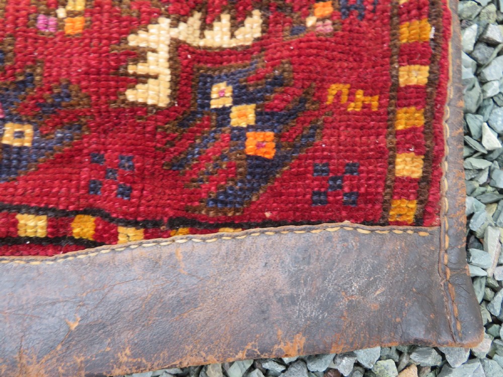 A late 19th-century Eastern Anatolian Yuruk double saddlebag woven in red, navy, and orange geometric wool patterns with leather binding. View X