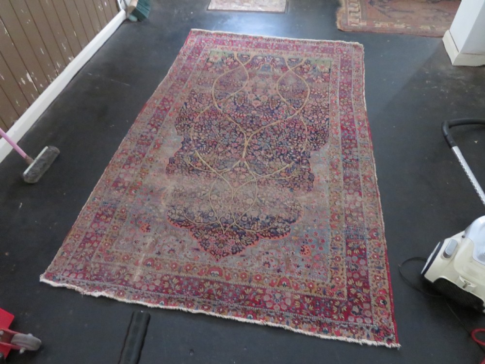 An antique hand-knotted Persian Kerman prayer rug featuring a dark central niche filled with millefleurs floral motifs and a crimson border. View XXIV