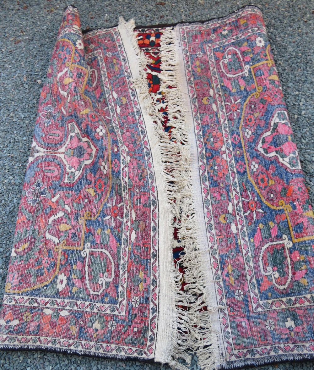 An antique Bakhtiari wool rug featuring a cream and pink central floral medallion framed by red and navy blue fields with complex botanical borders. View XVII