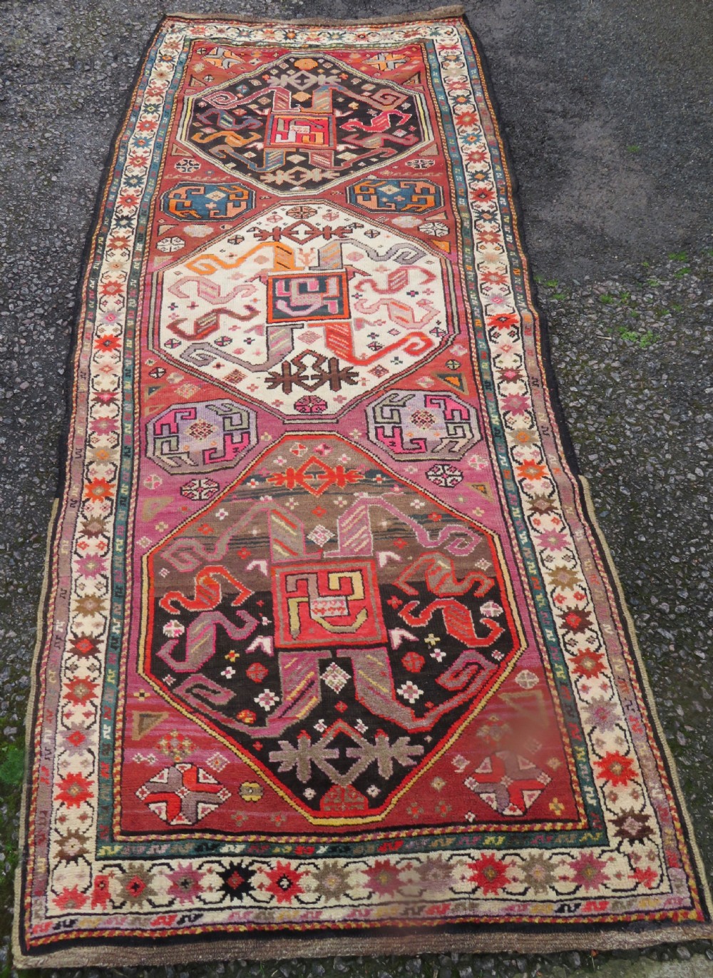 An antique hand-knotted Caucasian Karabagh Chondoresk long runner featuring bold geometric cloudband medallions in shades of red, black, and cream with an ornate decorative border. View II