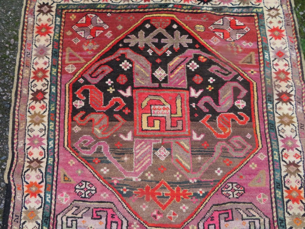 An antique hand-knotted Caucasian Karabagh Chondoresk long runner featuring bold geometric cloudband medallions in shades of red, black, and cream with an ornate decorative border. View III