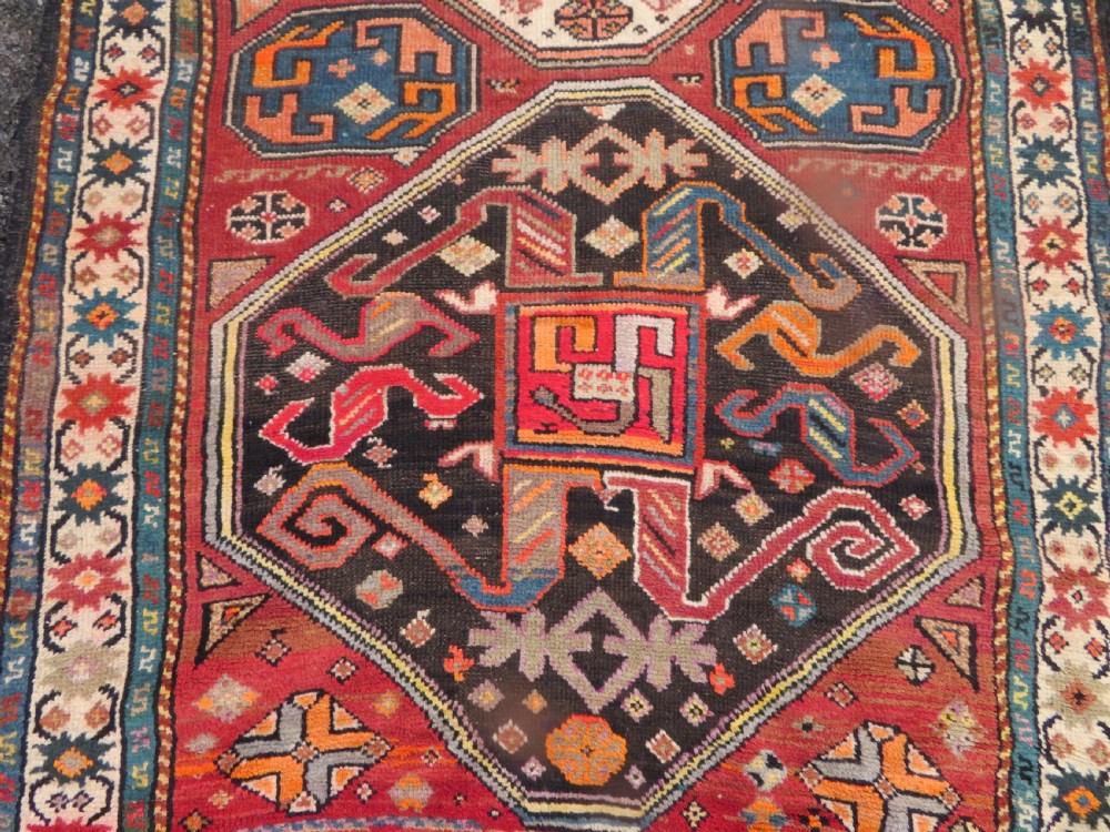 An antique hand-knotted Caucasian Karabagh Chondoresk long runner featuring bold geometric cloudband medallions in shades of red, black, and cream with an ornate decorative border. View IV