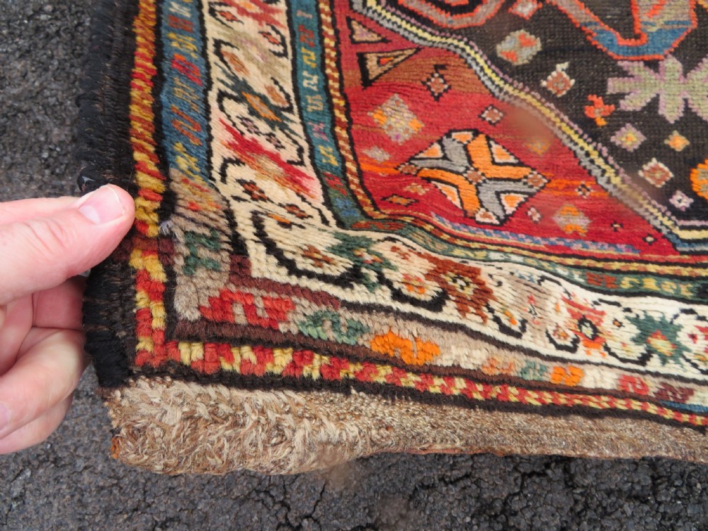 An antique hand-knotted Caucasian Karabagh Chondoresk long runner featuring bold geometric cloudband medallions in shades of red, black, and cream with an ornate decorative border. View V