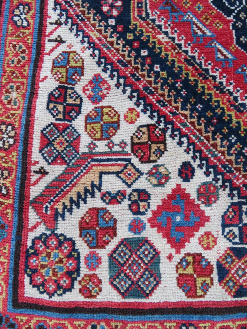An antique hand-knotted Qashqai Kashkuli wool rug featuring three stacked diamond medallions in red, indigo blue, and ivory surrounded by intricate geometric borders. View V