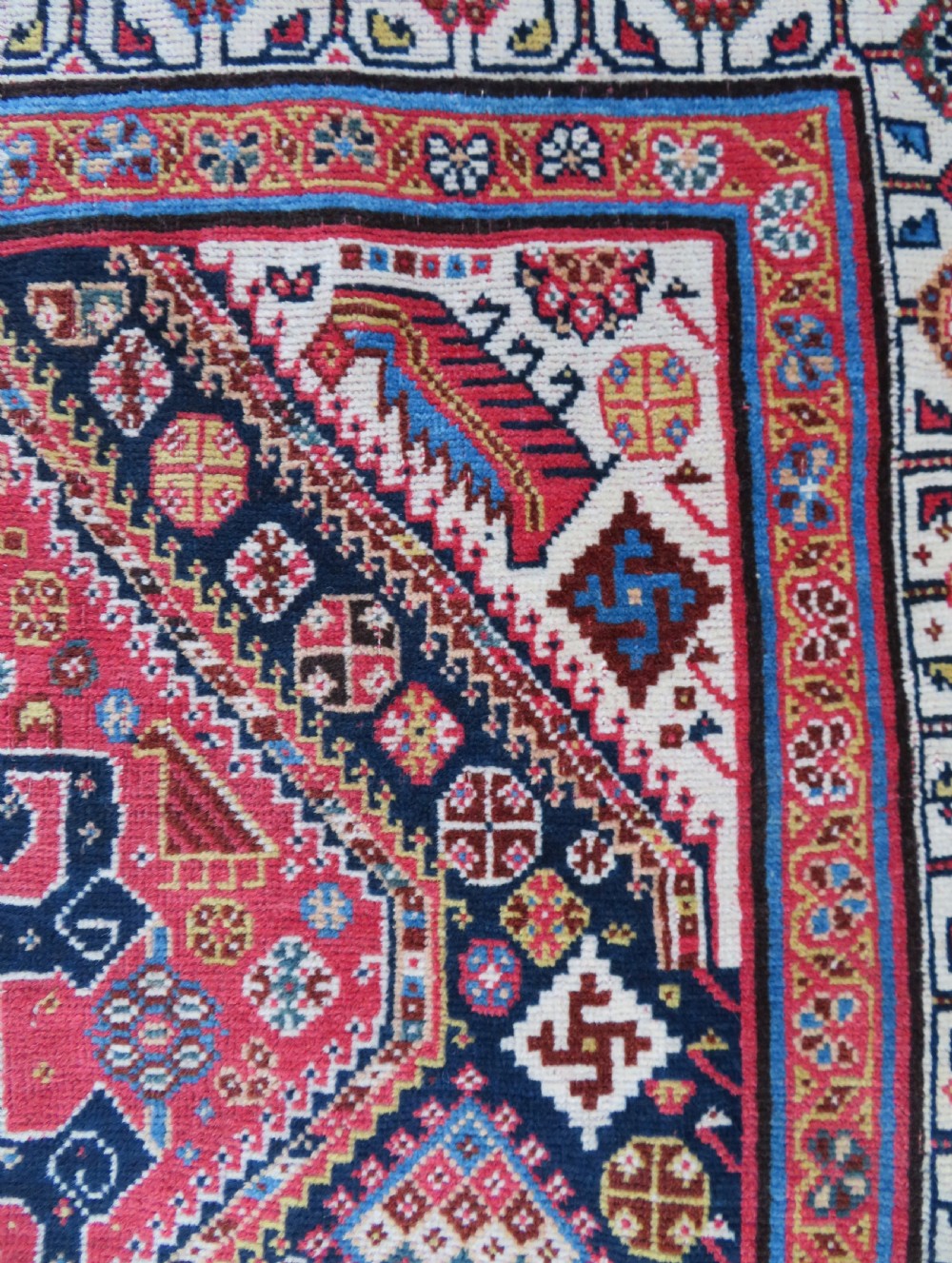 An antique hand-knotted Qashqai Kashkuli wool rug featuring three stacked diamond medallions in red, indigo blue, and ivory surrounded by intricate geometric borders. View XII