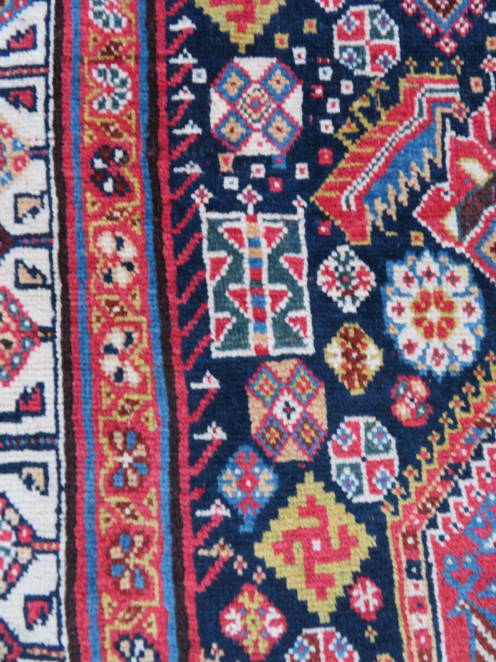 An antique hand-knotted Qashqai Kashkuli wool rug featuring three stacked diamond medallions in red, indigo blue, and ivory surrounded by intricate geometric borders. View XVII