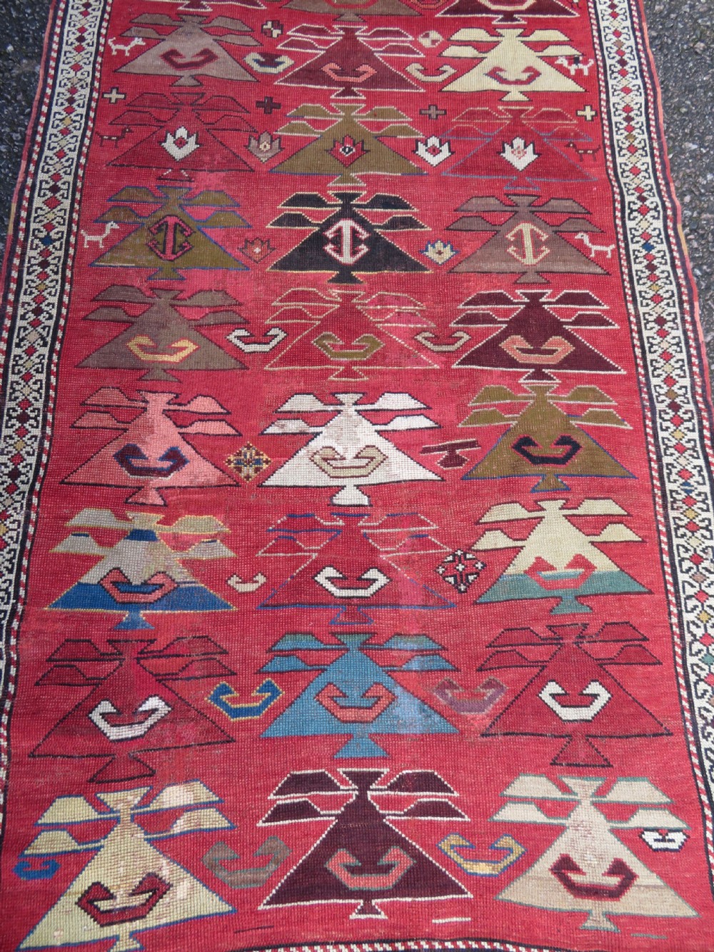 An antique South Caucasian Karabagh hand-knotted wool rug with repeating geometric motifs across a deep red field and a patterned border. View III