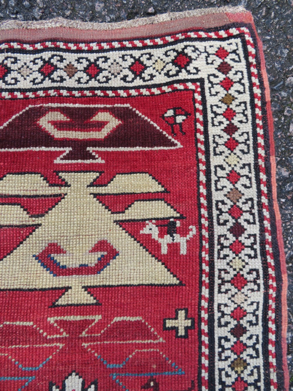 An antique South Caucasian Karabagh hand-knotted wool rug with repeating geometric motifs across a deep red field and a patterned border. View IV