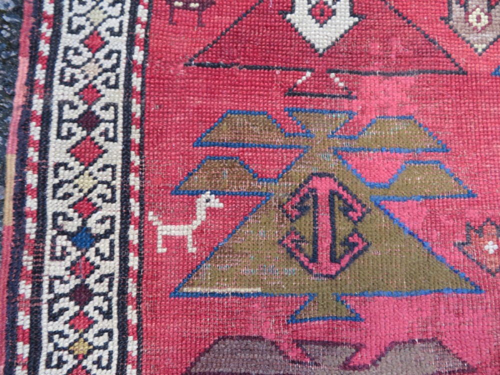 An antique South Caucasian Karabagh hand-knotted wool rug with repeating geometric motifs across a deep red field and a patterned border. View V