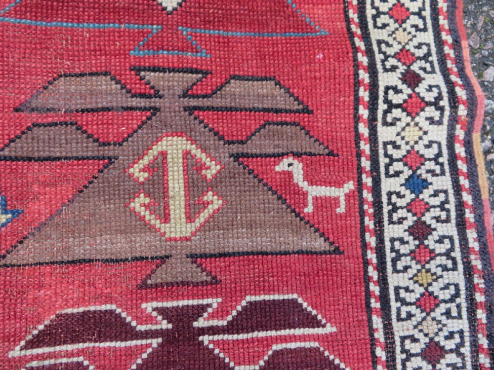 An antique South Caucasian Karabagh hand-knotted wool rug with repeating geometric motifs across a deep red field and a patterned border. View VII